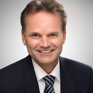 Mann mittleren Alters in einem dunklen Anzug mit gestreifter Krawatte