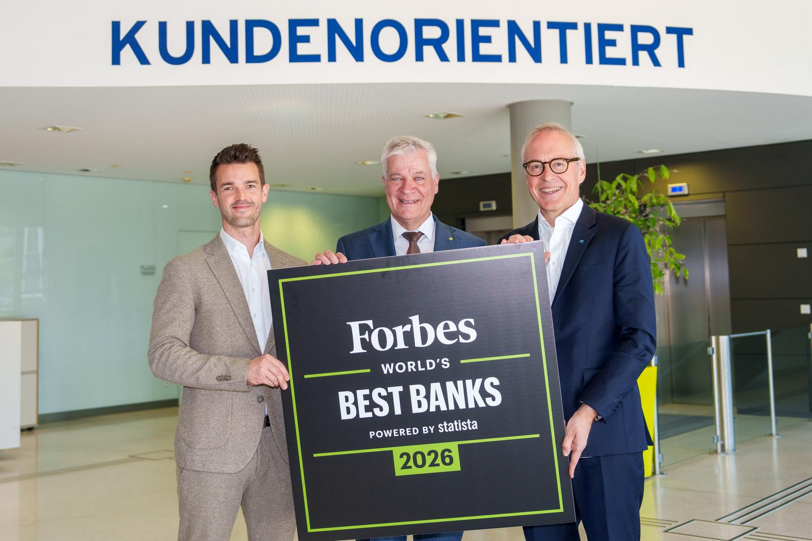 drei Männer in Anzug und Krawatte halten ein Schild mit der Aufschrift "Forbes World's Best Banks"