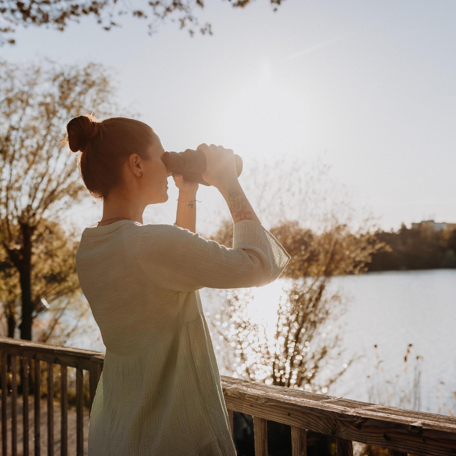 Frau mit Fernglas am See