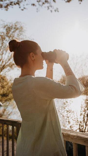 Frau mit Fernglas am See