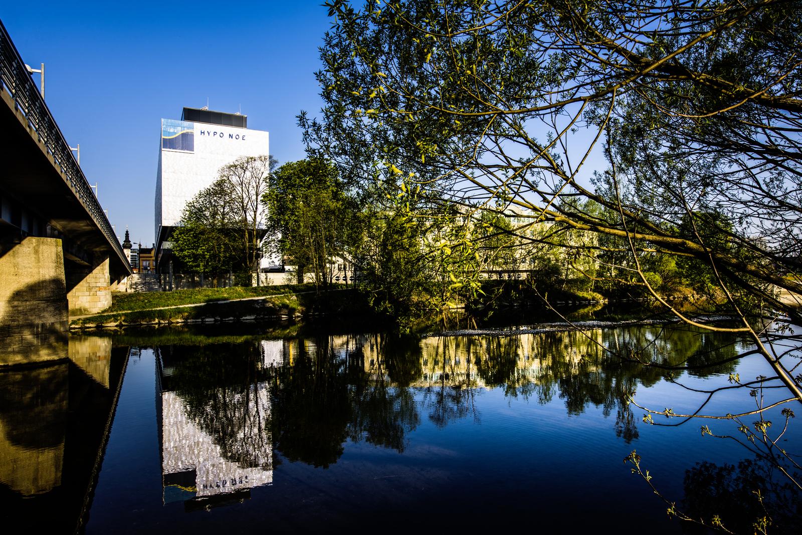 HYPO NOE Zentrale - weißes mehrstöckiges Bürogebäude mit dem Fluss Traisen im Vordergrund