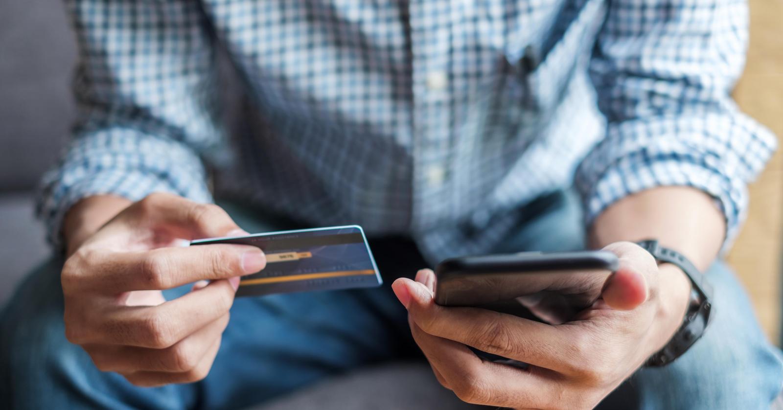 Ein Mann nimmt sein Smartphone in die Hand, um sich rasche Hilfe auf Grund von Kartenverlust zu holen.