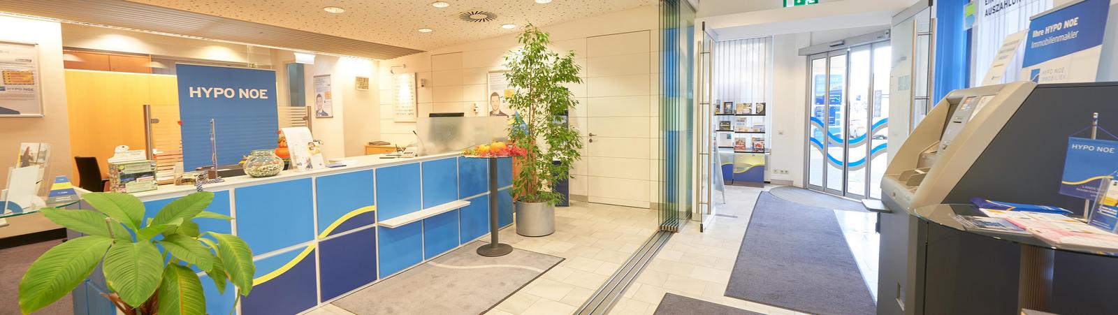 Raum der Filiale, links ist ein Schalter, geradeaus der Eingag und rechts steht ein Bankomat.