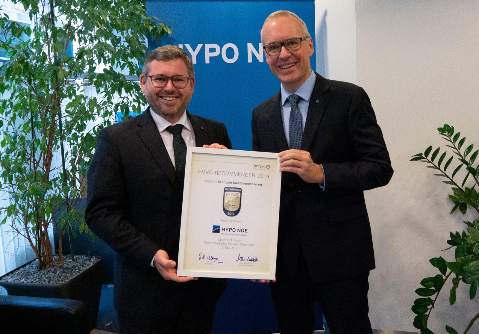 Zwei Männer mittleren Alters in Anzug und Krawatte halten eine Urkunde mit der Aufschrift "FMVÖ-Recommender: Award für sehr gute Kundenorientierung"