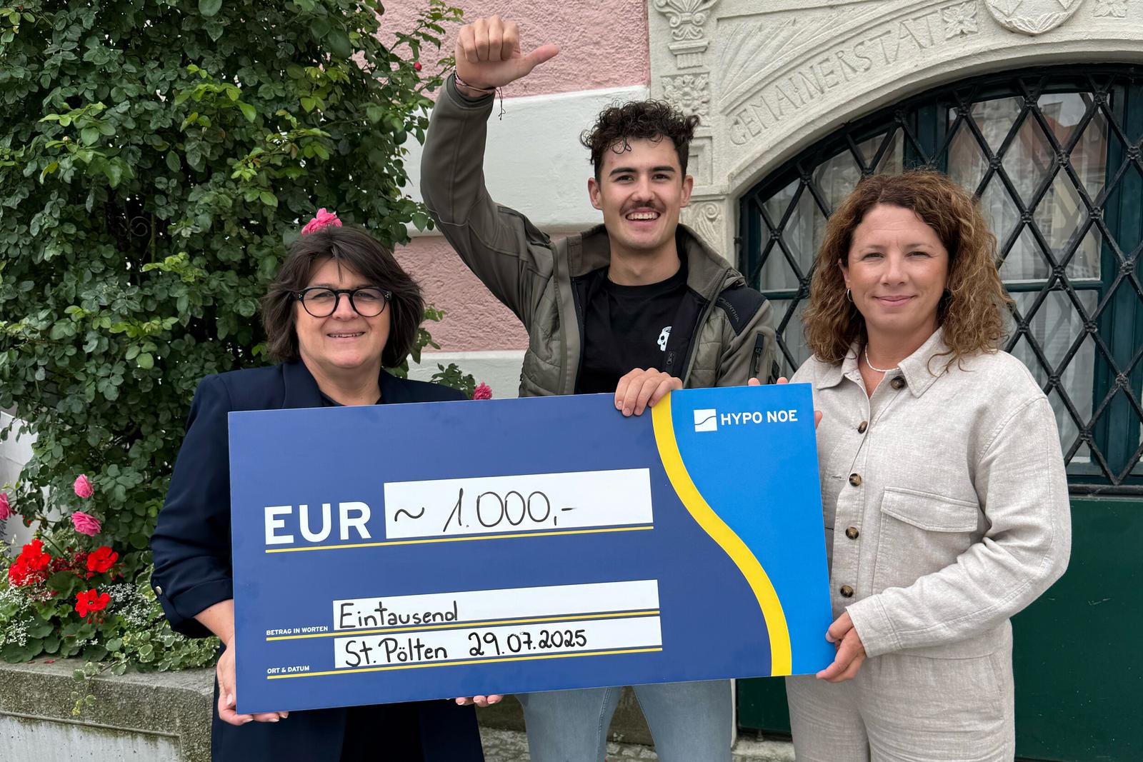 Zwei Frauen und ein junger Mann halten einen Scheck mit der Spende über 1.000 Euro.