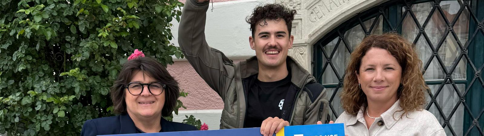 Zwei Frauen und ein junger Mann halten einen Scheck mit der Spende über 1.000 Euro.