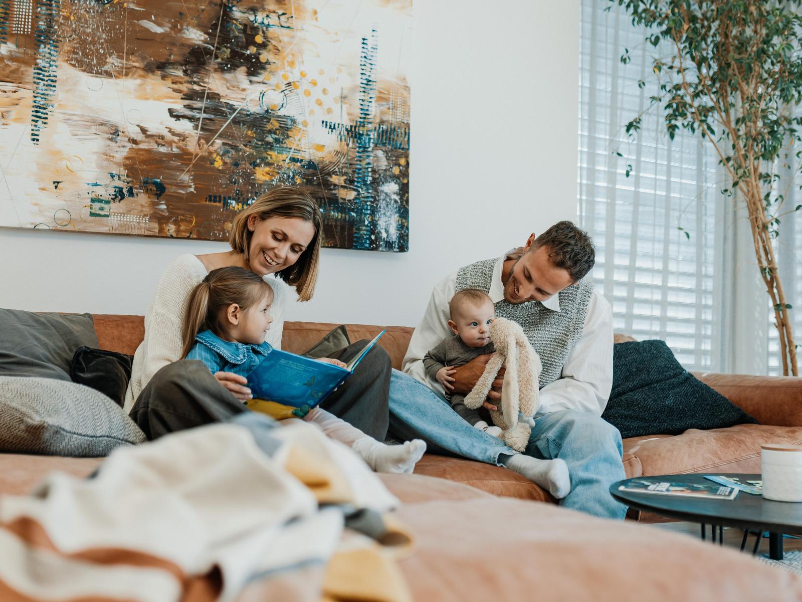 Vater, Mutter und Kinder spielen auf einer Couch