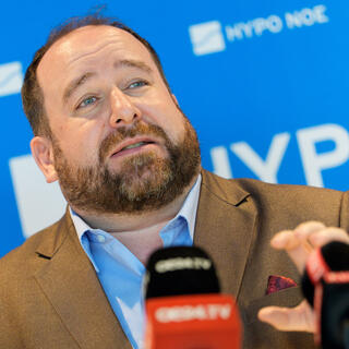 Pressekonferenz Immobilienbarometer 2026 Person spricht vor Mikrofonen bei einer Pressekonferenz von HYPO NOE.