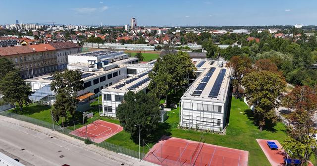 Lufansicht von zwei länglichen weißen Gebäuden mit Sport- und Grünflächen im Vordergrund
