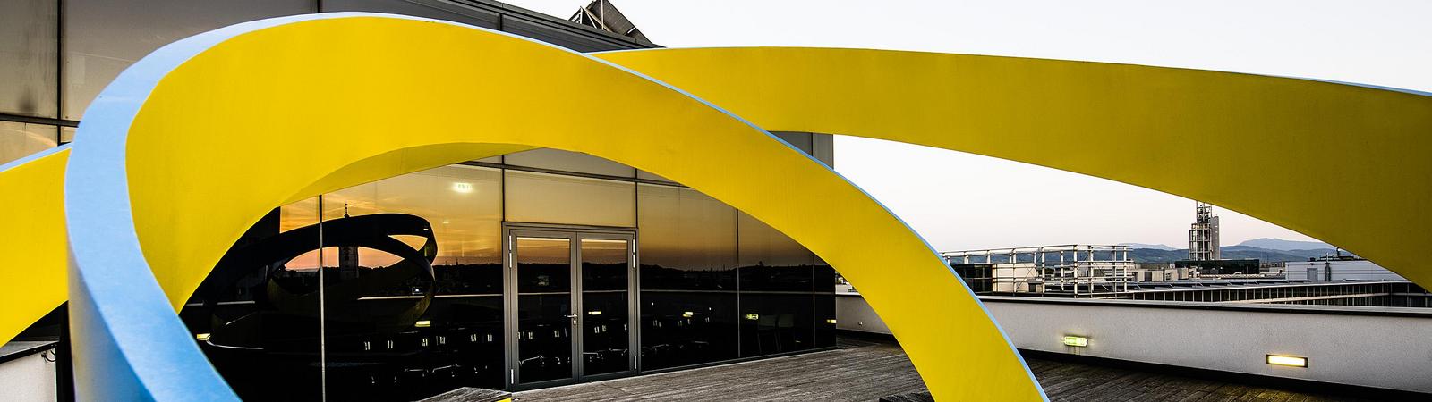 Skulptur aus gelb-blauen Wellen vor der HYPO NOE Konzernzentrale in St. Pölten