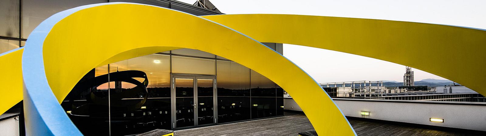 Skulptur aus gelb-blauen Wellen vor der HYPO NOE Konzernzentrale in St. Pölten