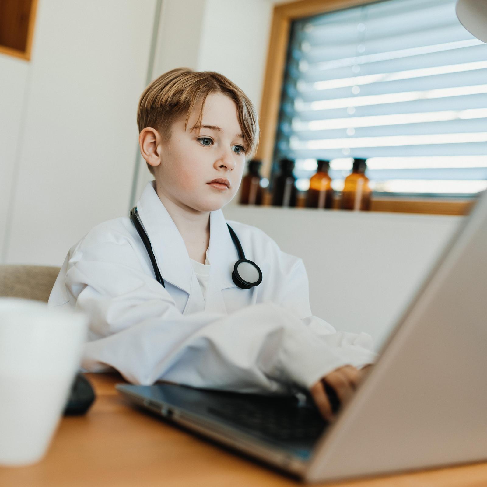 Bub sitzt verkleidet als Arzt am PC