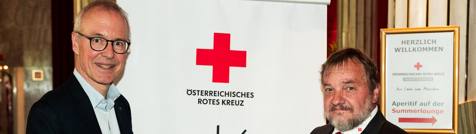 Zwei Männer in Anzug und Krawatte halten eine Urkunde.