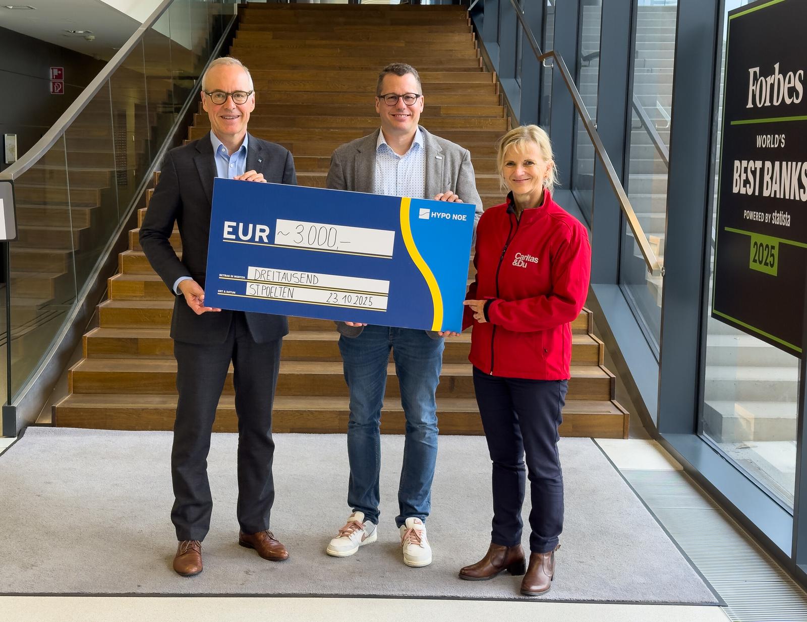 Zwei Männer und eine Frau halten einen Spendenscheck mit der Aufschrift 3.000 Euro.