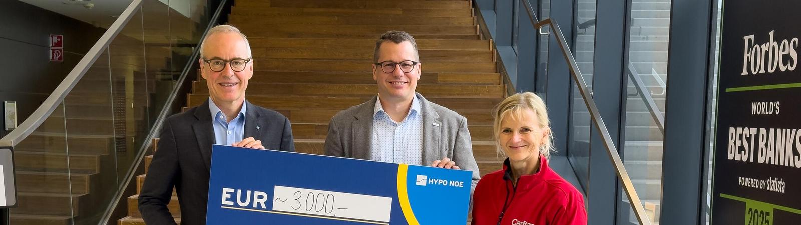 Zwei Männer und eine Frau halten einen Spendenscheck mit der Aufschrift 3.000 Euro.