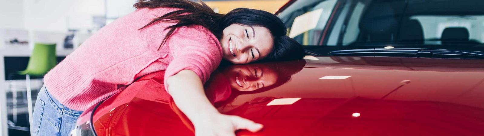 Eine Frau umarmt ihr neues mit der HYPO NOE finanziertes Auto