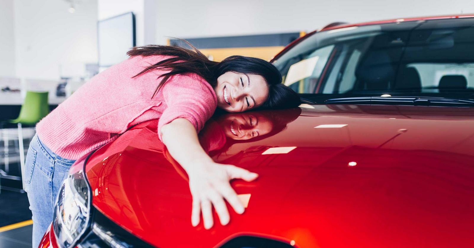 Frau umarmt rotes Auto