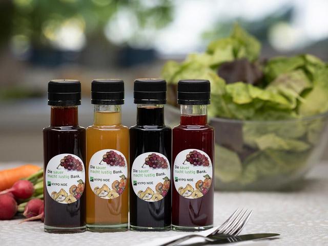 vier Essigfläschen stehen vor einer Salatschüssel