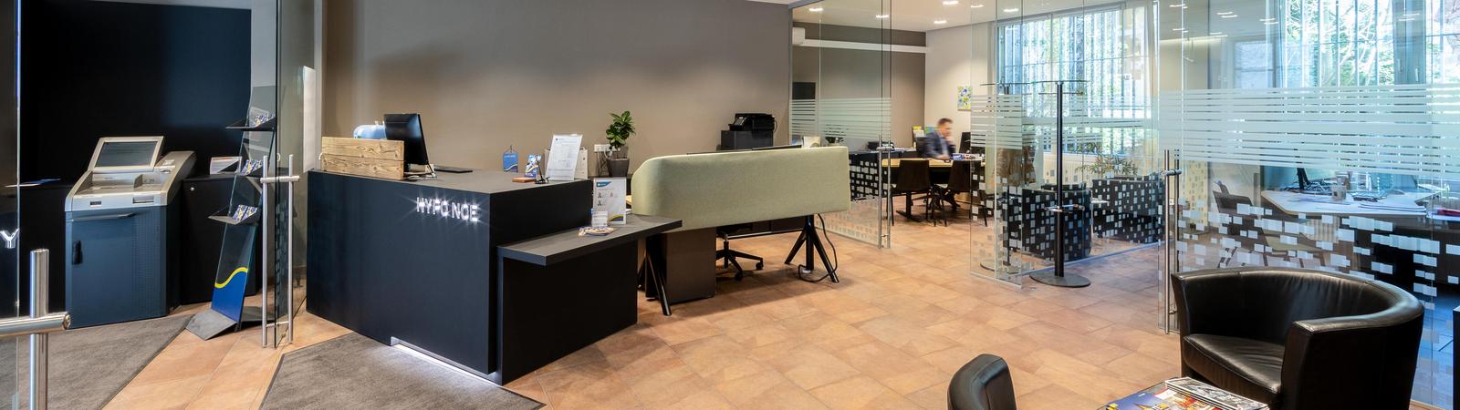 Foyer der Filiale, links ist ein Bankomat, geradeaus der Schalter und rechts ist eine Sitzecke.