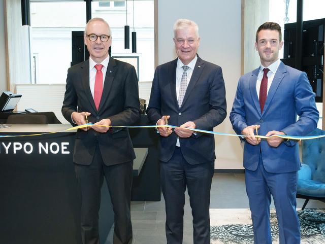 Gruppenfoto von drei Männer beim Durchschneiden eines blau-gelben Bandes.