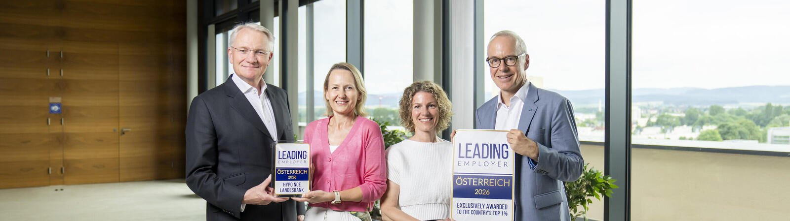 Zwei Männer im Anzug und zwei Frauen in Kleider halten eine Auszeichnung in die Kamera.
