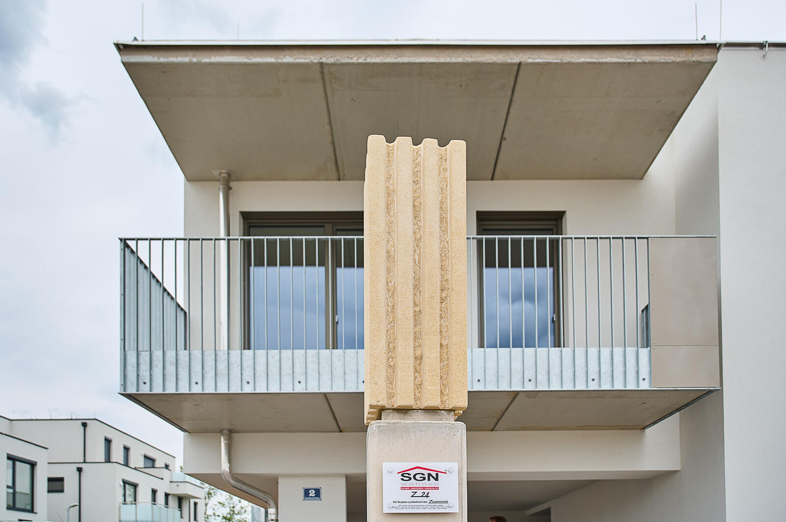 Modernes weißes Wohnhaus mit Balkonen und großen Fenstern.