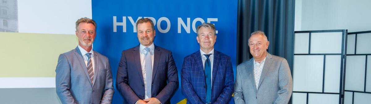 Vier Männer in Anzug und Krawatte stehen vor einem blauen HYPO NOE Banner.