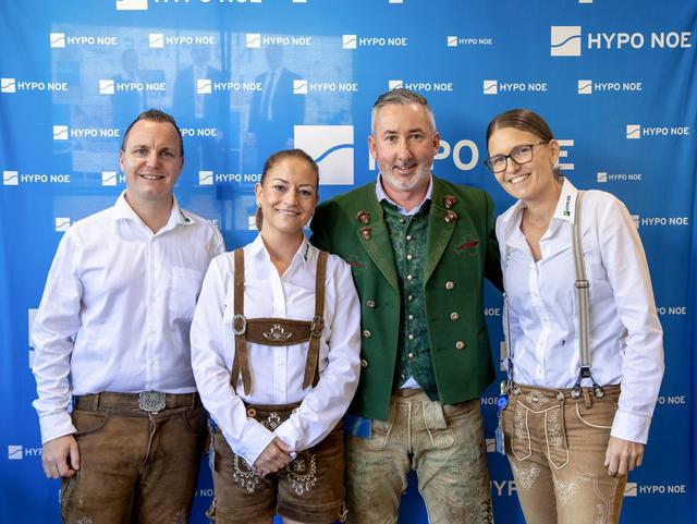 Eine Gruppe von 2 Männern und 2 Frauen steht vor einer blauen Wand mit Aufschrift "HYPO NOE".