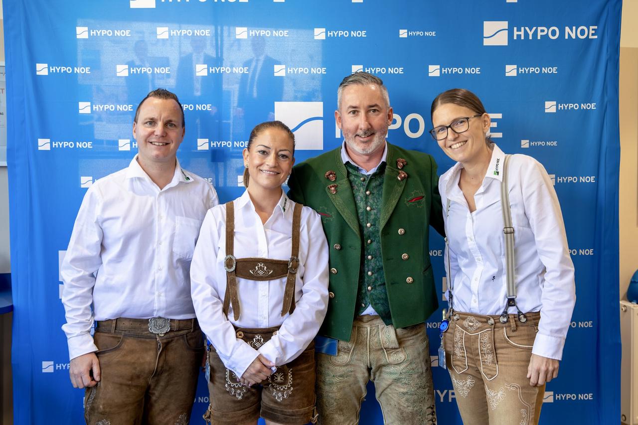 Eine Gruppe von 2 Männern und 2 Frauen steht vor einer blauen Wand mit Aufschrift "HYPO NOE".