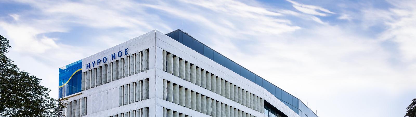 Ein weißes mehrstöckiges Bürogebäude mit Grünfläche und Bäumen davor