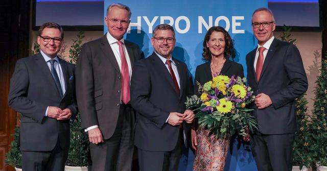 Eine Gruppe von vier Männern in Anzug und Krawatte und einer Frau auf einem Podium