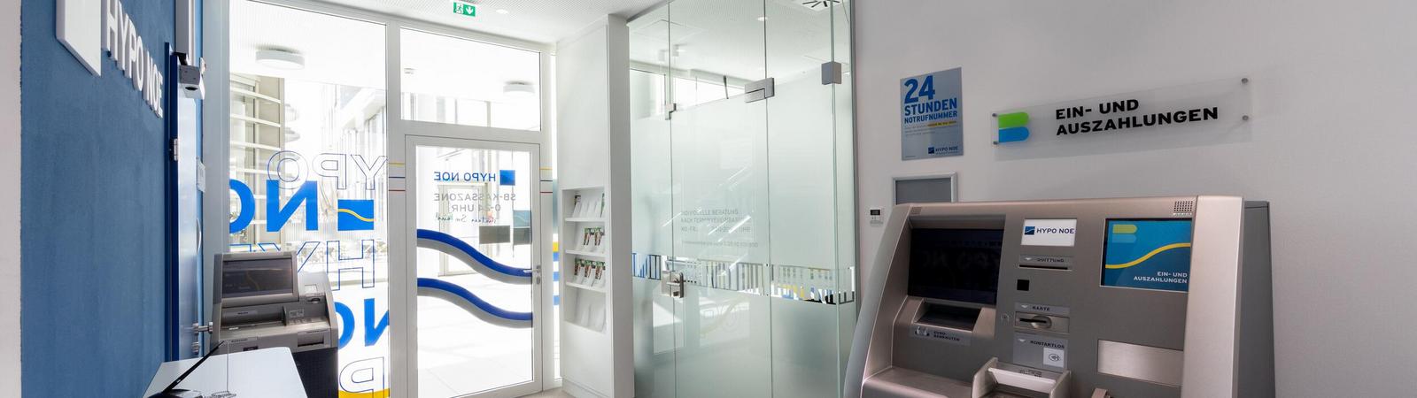 Raum mit Kontoauszugsdrucker und Bankomat, geradeaus sind zwei Türen zu sehen.