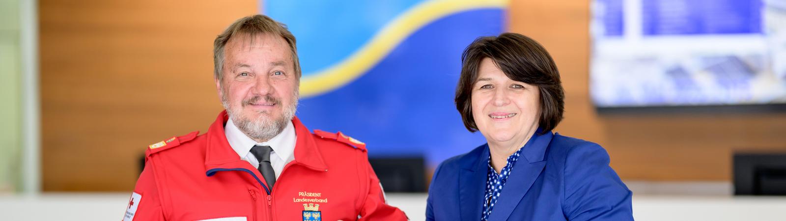 Ein älterer Mann in roter Jacke und eine Frau mittleren Alters halten einen Spendenscheck der HYPO NOE über 10.000 Euro.