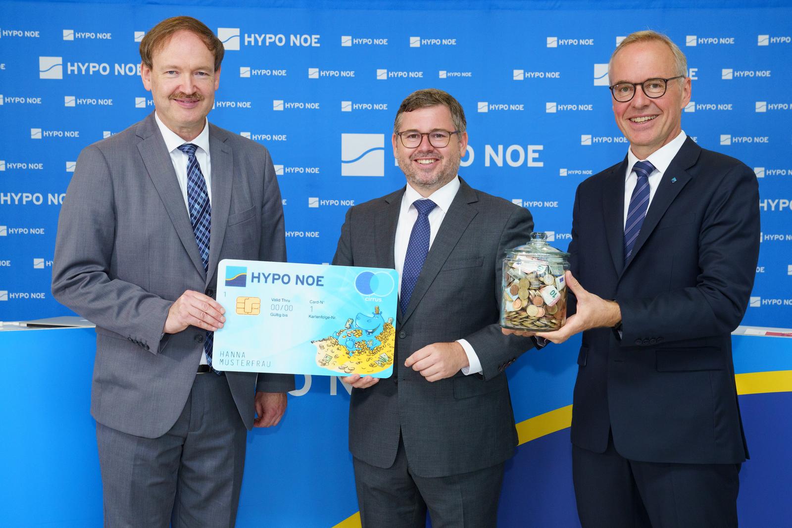 drei Männer mittleren Alters in Anzug und Krawatte mit einer Karte und einem Glas mit Münzen