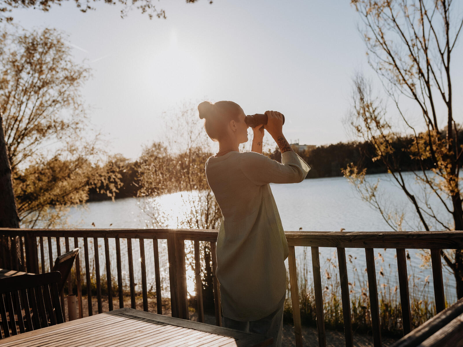 Mensch hält Fernglas am See