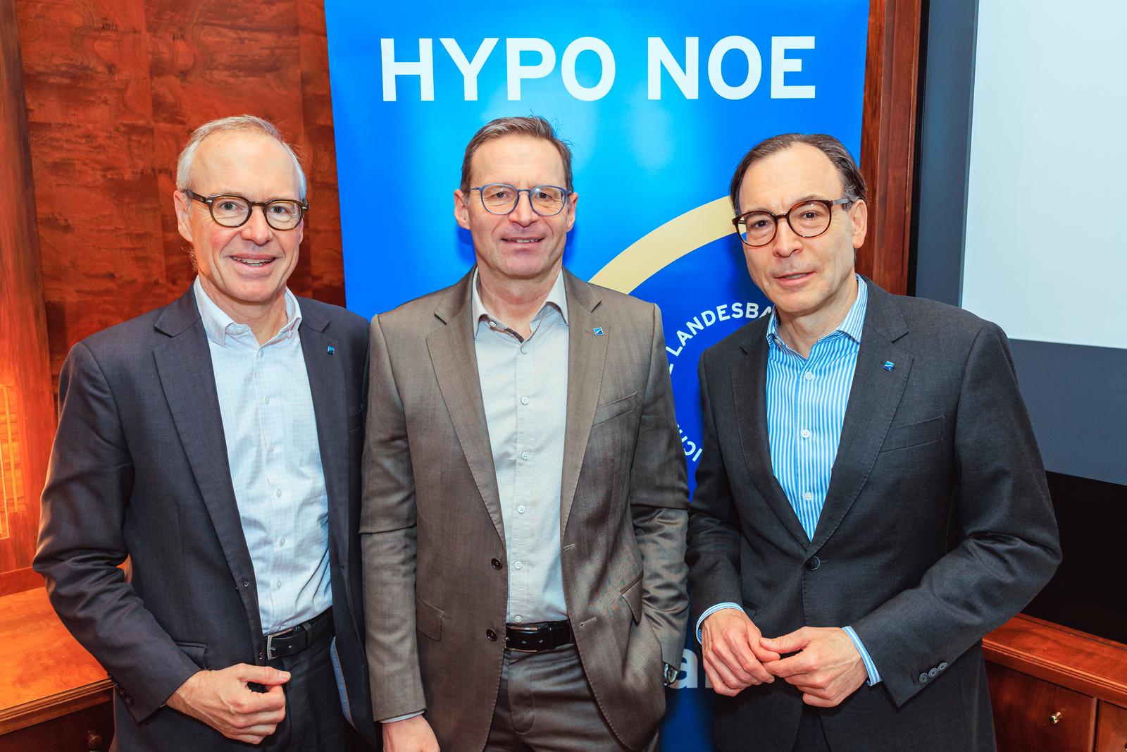 Drei Männer mittleren Alters in Anzügen stehen vor einem blauen Banner mit der Aufschrift "HYPO NOE".