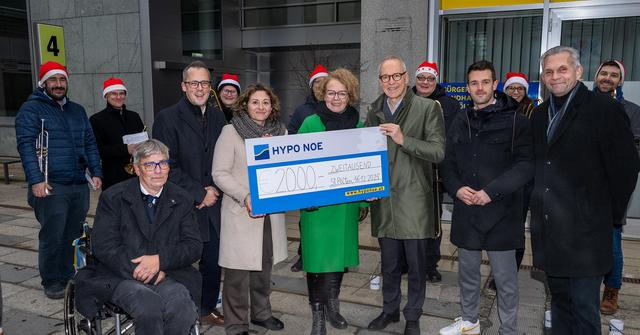 Ein Gruppe von Männern und Frauen bei einer Spendenscheckübergabe.