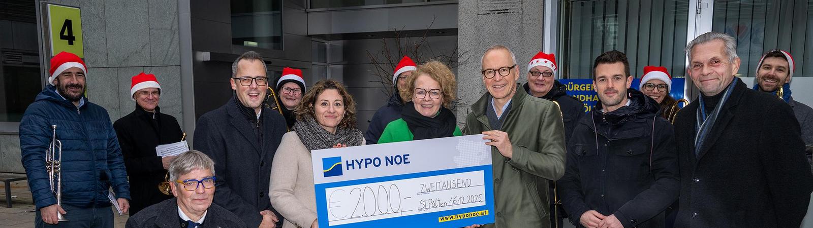 Ein Gruppe von Männern und Frauen bei einer Spendenscheckübergabe.