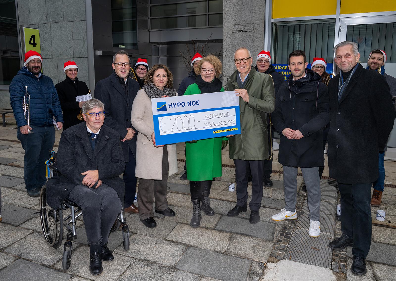 Ein Gruppe von Männern und Frauen bei einer Spendenscheckübergabe.