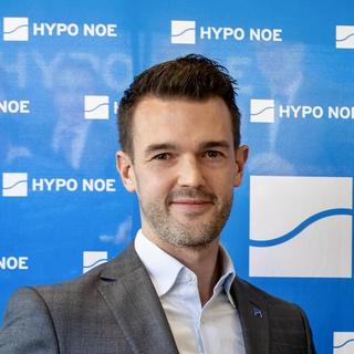 10 Jahre Filiale Schwechat 2 Männern und 2 Frauen steht vor einer blauen Wand mit Aufschrift "HYPO NOE" und halten eine Torte in die Kamera.