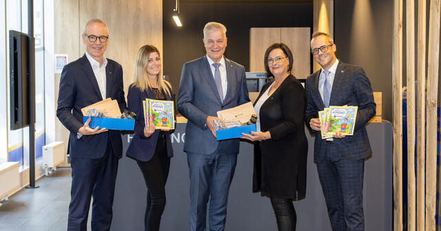 Zwei Frauen und drei Männer halten Geschenkboxen und Malbücher in der Hand.