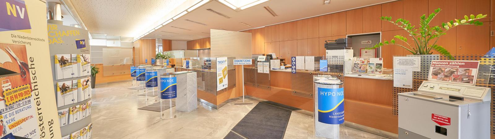 Kassenraum einer Bankfiliale mit viel Holz und einigen Bankschaltern.