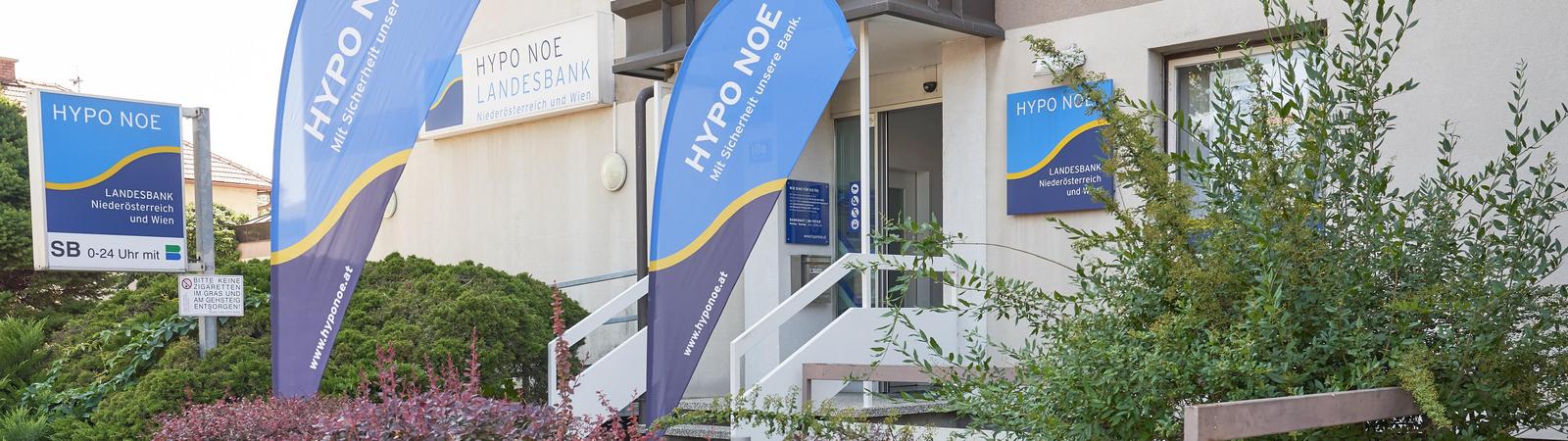 Außenansicht einer HYPO NOE Filiale mit HYPO NOE Flaggen auf dem Rasen.