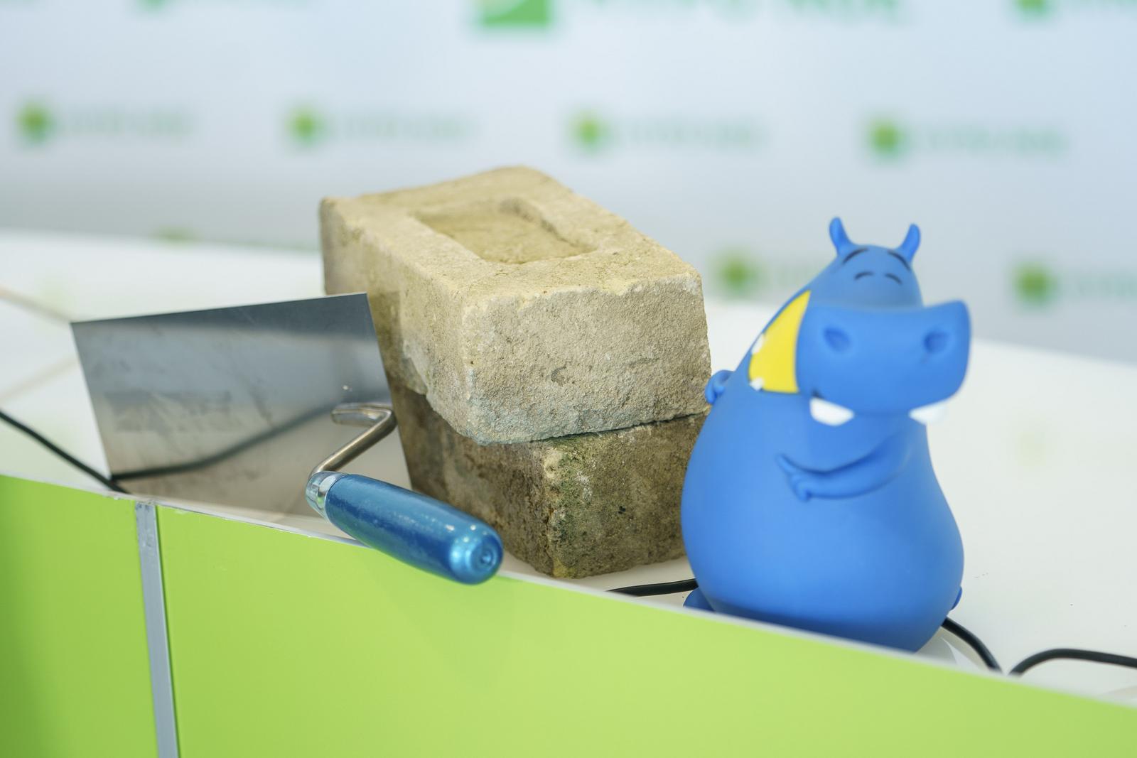 Mauerziegel eine Maurerkelle und eine Spardose in Form eines Flußpferdes