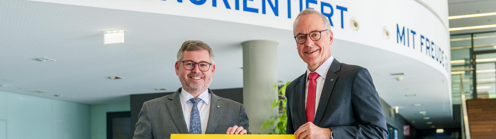 Zwei Männer, Finanzlandesrat Ludwig Schleritzko und HYPO NOE Vorstand Wolfgang Viehauser, halten gemeinsam ein Schild mit dem HYPO NOE Logo