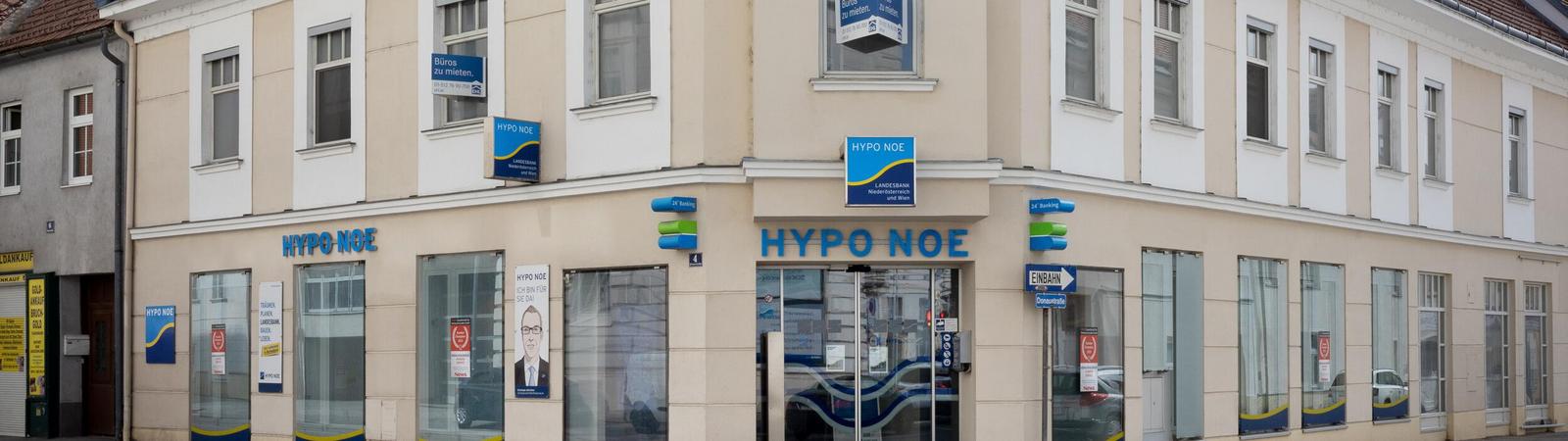 Außenansicht eines zweistöckigen rosafarbenen Gebäudes mit HYPO NOE Logo.