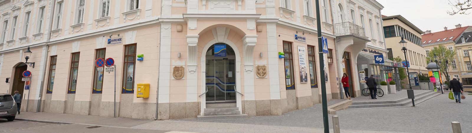 Außenansicht eines zweistöckigen rosafarbenen Gebäudes mit kleinem HYPO NOE Logo.